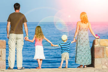 Happy parents with children playing on the sea background