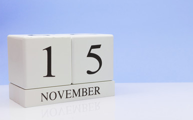 November 15st. Day 15 of month, daily calendar on white table with reflection, with light blue background. Autumn time, empty space for text