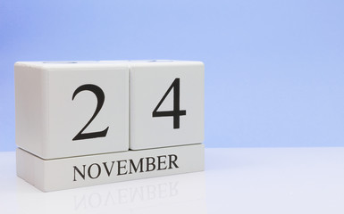 November 24st. Day 24 of month, daily calendar on white table with reflection, with light blue background. Autumn time, empty space for text