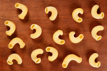 Dry uncooked cavatappi italian pasta, close up on brown wood background.