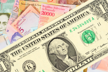 Large one-dollar bill against the background of many small Venezuelan banknotes. The concept of...