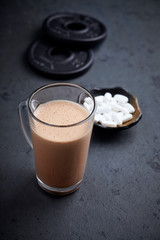 Chocolate Protein Shake, BCAA amino acids and plates. Nutrition for bodybuilding. Black stone background. Copy space.