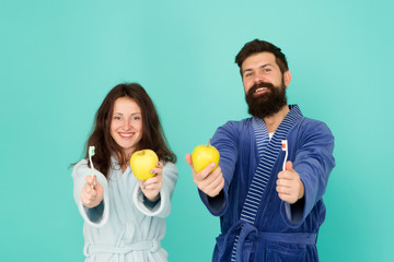 Brush teeth concept. Oral hygiene. Couple in bathrobes hold toothbrushes and apples. Man girl care hygiene. First rule of personal hygiene. Couple in love cleaning teeth every morning. Healthy smile