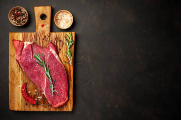 raw new york steak with ingredients on a cutting board. on the background of dark stone.with copy space