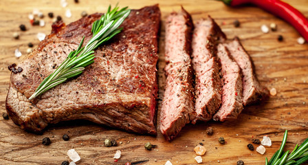 Ready to eat New York black angus steak with ingredients on a cutting board. Ready meal for dinner on a dark stone background.