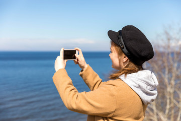 Cute girl takes pictures on a smartphone sights in solo travel. Share your impressions!