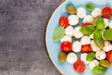 Delicious caprese salad with ripe cherry tomatoes and mini mozzarella cheese balls with fresh basil leaves.
