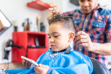 Cute Boy Getting a Hair Cut in a Barber Shop. Beauty Concept.