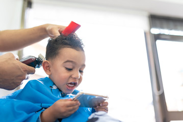 Cute Boy Getting a Hair Cut in a Barber Shop. Beauty Concept.