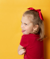 emotional little girl turned her back and shows her tongue out over her shoulders.