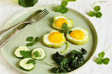 green breakfast on St. Patrick's Day. eggs in the form of clover. Fried Eggs Shamrock  in Green Pepper rings with Braised Spinach. parsley leaves like clover leaves.
