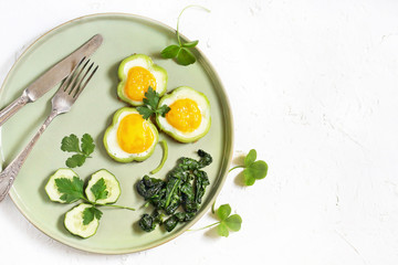green breakfast on St. Patrick's Day. eggs in the form of clover. Fried Eggs Shamrock  in Green Pepper rings with Braised Spinach. parsley leaves like clover leaves.