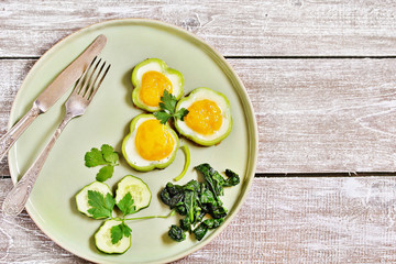 green breakfast on St. Patrick's Day. eggs in the form of clover. Fried Eggs Shamrock  in Green Pepper rings with Braised Spinach. parsley leaves like clover leaves.