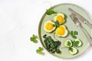 green breakfast on St. Patrick's Day. eggs in the form of clover. Fried Eggs Shamrock  in Green Pepper rings with Braised Spinach. parsley leaves like clover leaves.
