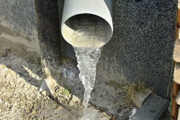 closeup frozen water in gray house gutter in winter weather on the city street