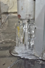 Naklejka na ściany i meble closeup frozen water in gray house gutter in winter weather on the city street