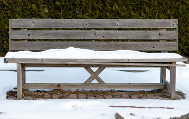 Old rusty  pine wood bench empty  in park  covered white snow  during winter