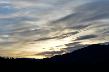 Cloudy  dramatic sky over silhouette landscape during winter at sunset