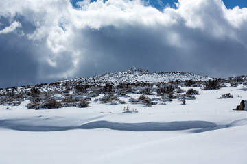 Snow covered desert landscape with puffy clouds and blue sky