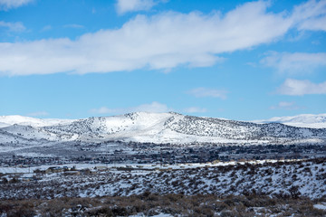 Snow covered desert landscape with puffy clouds and blue sky