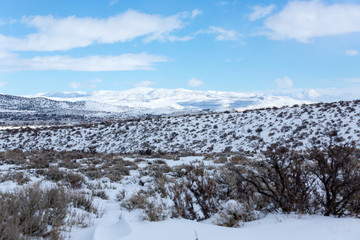 Snow covered desert landscape with puffy clouds and blue sky