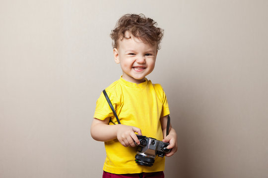 Little kid boy 2 years old wearing yellow clothes hold camera isolated on grey wall background, children studio portrait. People sincere emotions, childhood lifestyle concept.