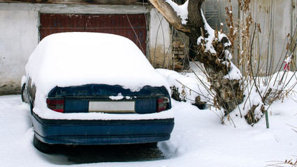 Car in the snow near the garage.