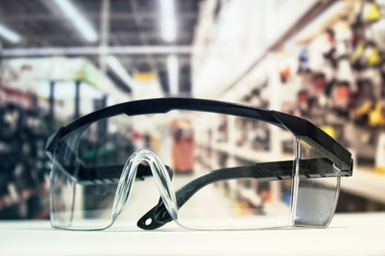 Plastic safety goggles, on the table and background of the hardware store with tools.