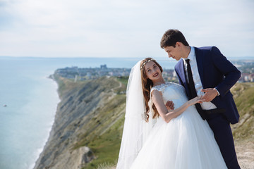 Beautiful couple of newlywed hugging at wedding day on cliff with ocean view