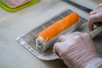 Cook hands making japanese sushi roll. Japanese chef at work preparing delicious sushi roll with eel and avocado. Appetizing japanese food.