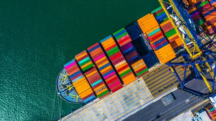 Container cargo freight ship with working crane bridge discharge at container terminal, Aerial top view container ship at deep sea port. © Kalyakan