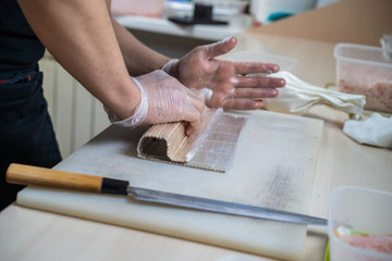 Cook hands making japanese sushi roll. Japanese chef at work preparing delicious sushi roll with eel and avocado. Appetizing japanese food.