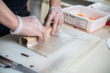 Cook hands making japanese sushi roll. Japanese chef at work preparing delicious sushi roll with eel and avocado. Appetizing japanese food.