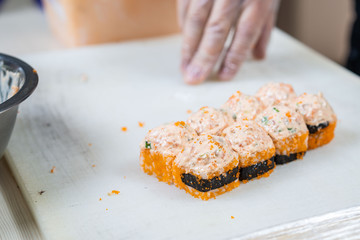 Cook hands making japanese sushi roll. Japanese chef at work preparing delicious sushi roll with eel and avocado. Appetizing japanese food.