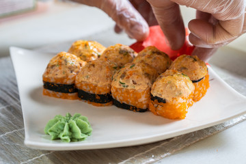 Cook hands making japanese sushi roll. Japanese chef at work preparing delicious sushi roll with eel and avocado. Appetizing japanese food.