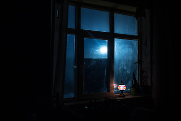 Night scene of stars seen through the window from dark room. Night sky inside dark room viewing from window with old vintage lantern. Long exposure shot © zef art