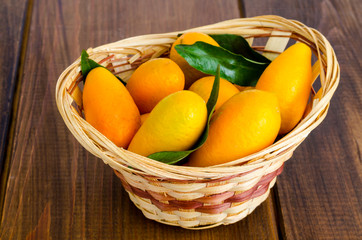 Ripe sweet orange kumquats fortunella in wooden basket.