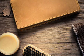 Vintage genuine leather wallet on wooden table prepare to clean and care with wax. maintenance concept. Men accessories on rustic wood.