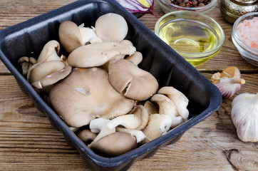 Fresh oyster mushrooms in packaging, spices for cooking.