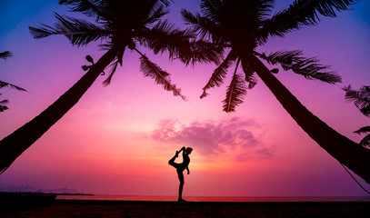 Beautiful young woman practic yoga at the beach. Early morning exercise. Sunrise
