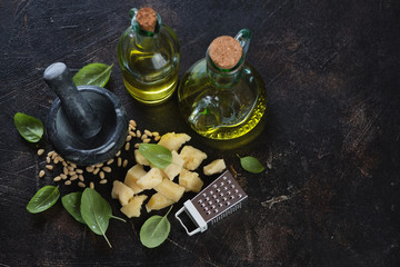 All the main components for cooking green basil pesto sauce, high angle view on a dark brown stone background with space