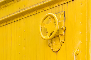industrial valve wheel on dirty yellow metal background