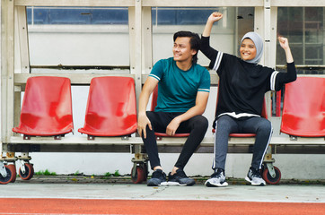 young couple sit in stadium with happy face expression, having fun and cheering to their team © amirul syaidi