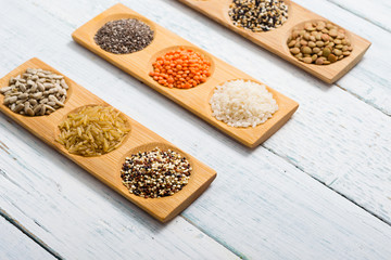 gluten free grains, seeds on bamboo plate, white wood table