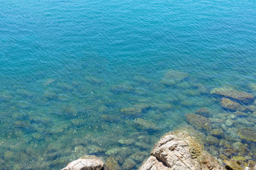 sea near coastlines, have many big stone with sun light shine on. for the sea is so clean and clear til can see things under