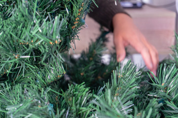 Hands unravelling an artificial Christmas tree without ornaments.