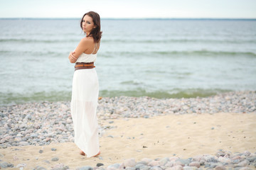 Fototapeta na wymiar Gorgeous dark-haired girl in dress on sandy beach