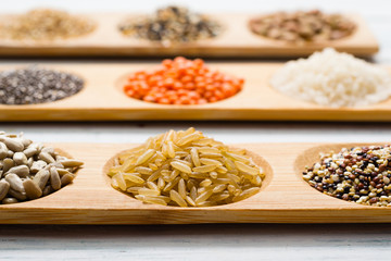 gluten free grains, seeds on bamboo plate, white wood table