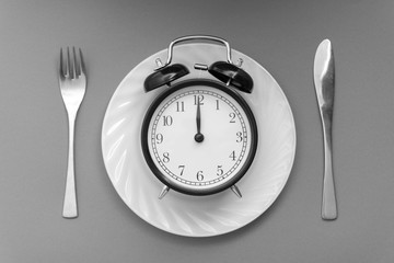 Alarm clock with fork and knife on the table. Time to eat, Breakfast, Lunch time and dinner concept. Black and White Concept