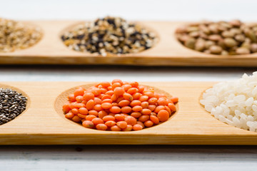 gluten free grains, seeds on bamboo plate, white wood table